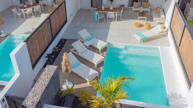 Un espace piscine aménagé sur le toit, avec des chaises longues, une table et un coin salon.