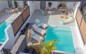 Un espace piscine aménagé sur le toit, avec des chaises longues, une table et un coin salon.