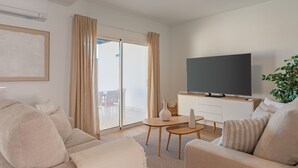 A modern living room with a sofa, a TV, a small table, and a plant.