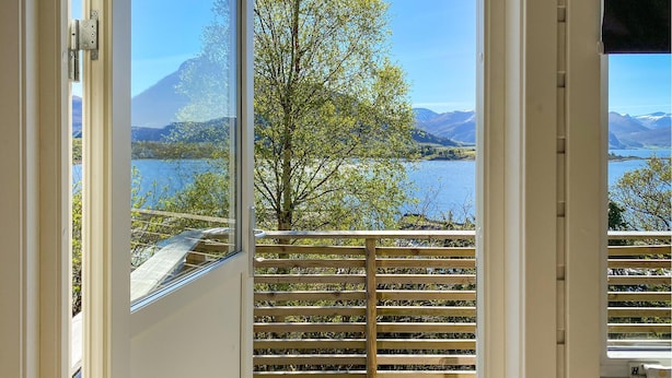A view from a balcony with a wooden railing, overlooking a lake and mountains. - 2 bedroom lovely home in ørsta (Ørsta)