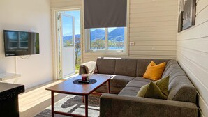 A modern living room with a grey sofa, a wooden coffee table, and a flat-screen TV mounted on the wall. - 2 bedroom lovely home in ørsta (Ørsta)