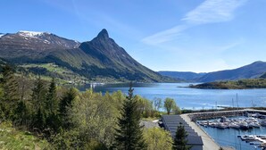 A marina with boats docked, surrounded by lush greenery and mountains in the background.
