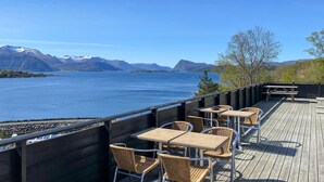 A deck with outdoor seating overlooking a lake and mountains.