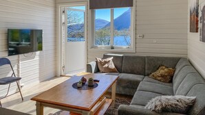 A cozy living room with a grey sofa, a wooden coffee table, and a television on the wall. - 2 bedroom lovely home in ørsta (Ørsta)