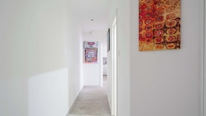 Un pasillo con un papel tapiz estampado, una puerta al final y un cartel en la pared.