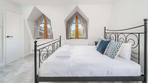 A bedroom with a bed, two windows, a radiator, and a door. - Beautiful 2 bed flat near Battersea park (London)