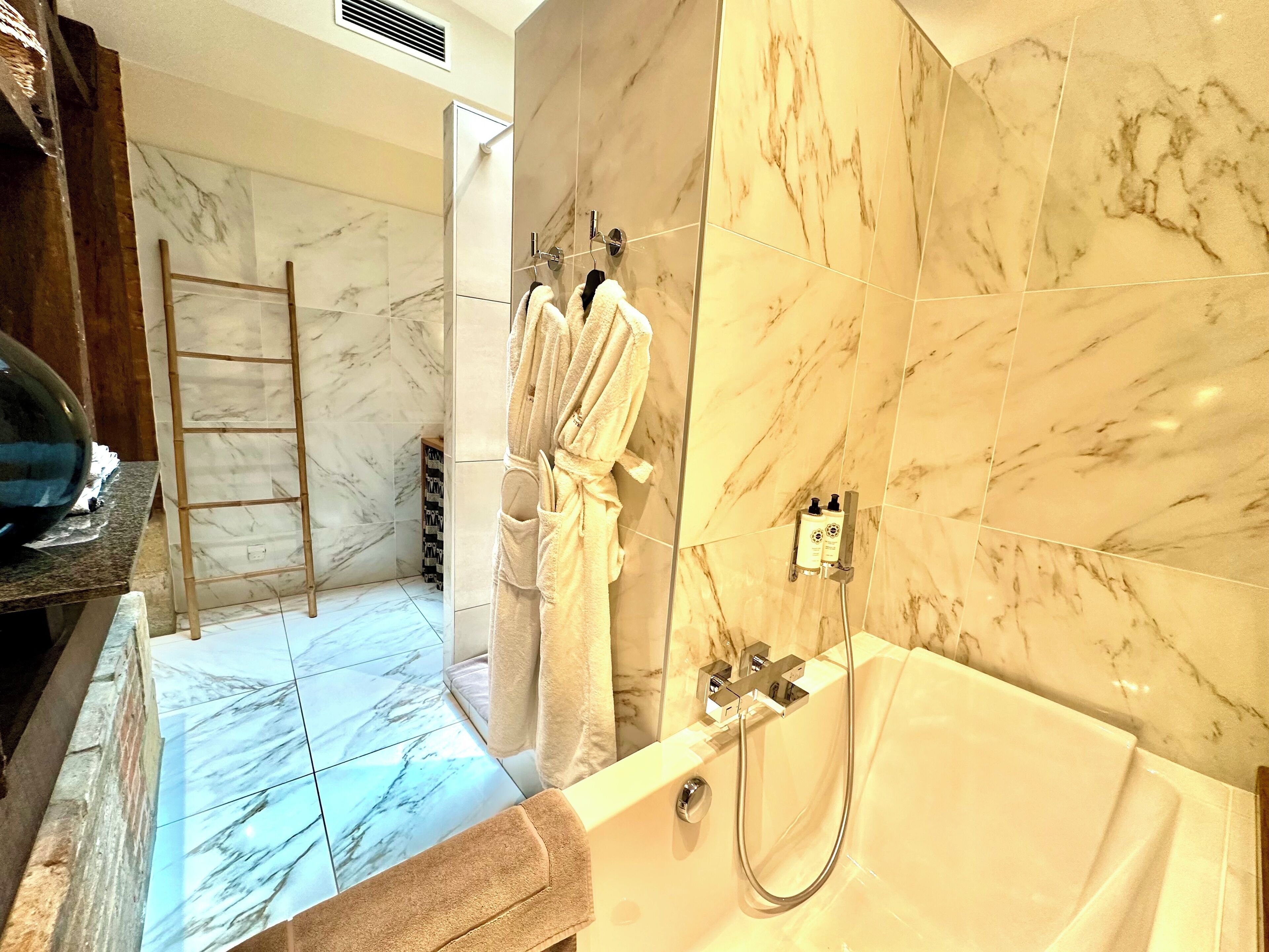 Un baño con suelo de mármol, bañera y zona de ducha.