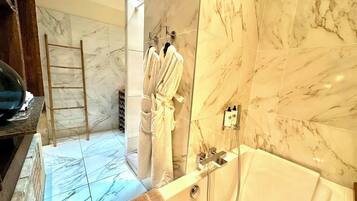 Un baño con suelo de mármol, bañera y zona de ducha.