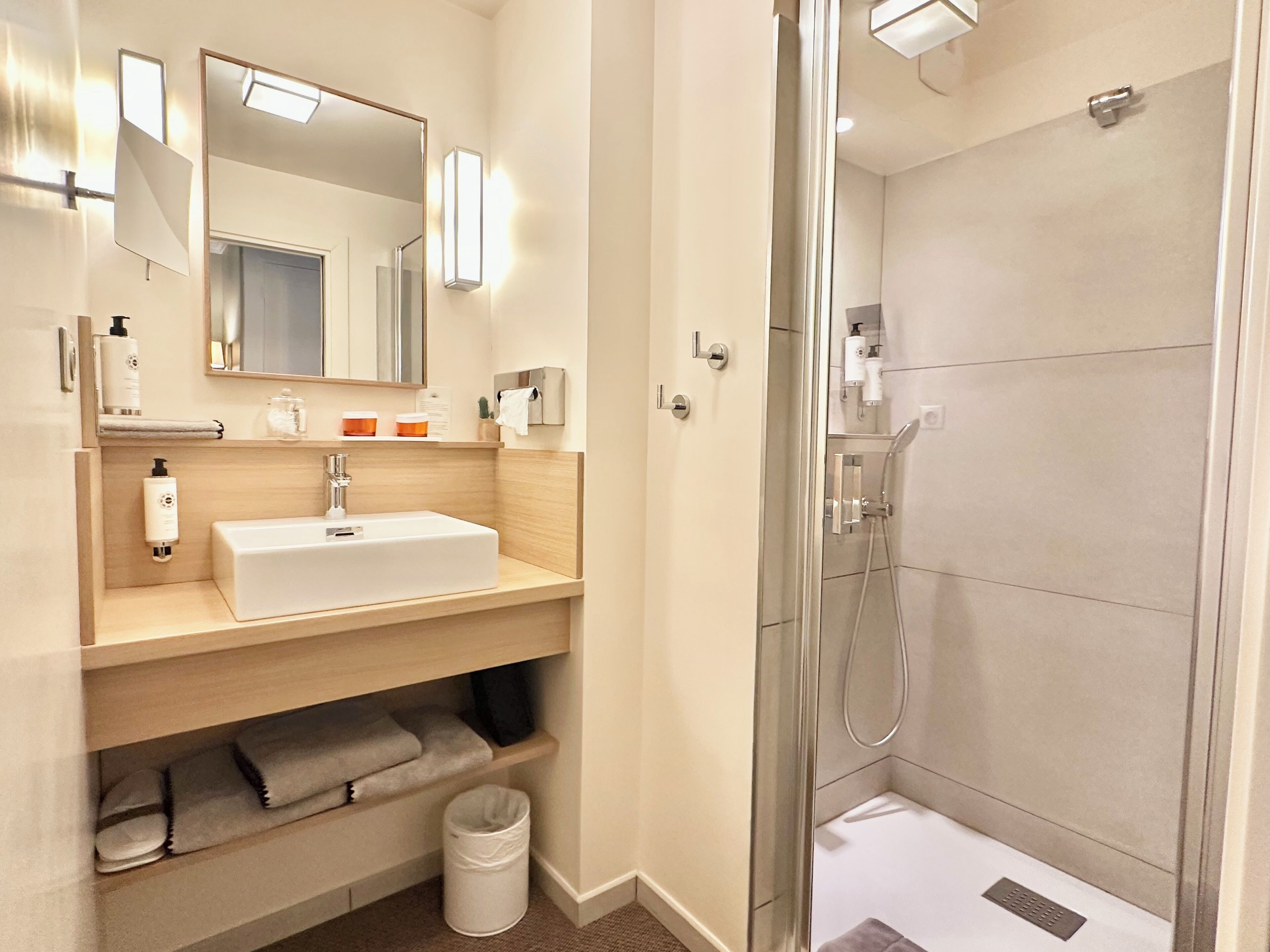 A modern bathroom with a sink, mirror, and shower.