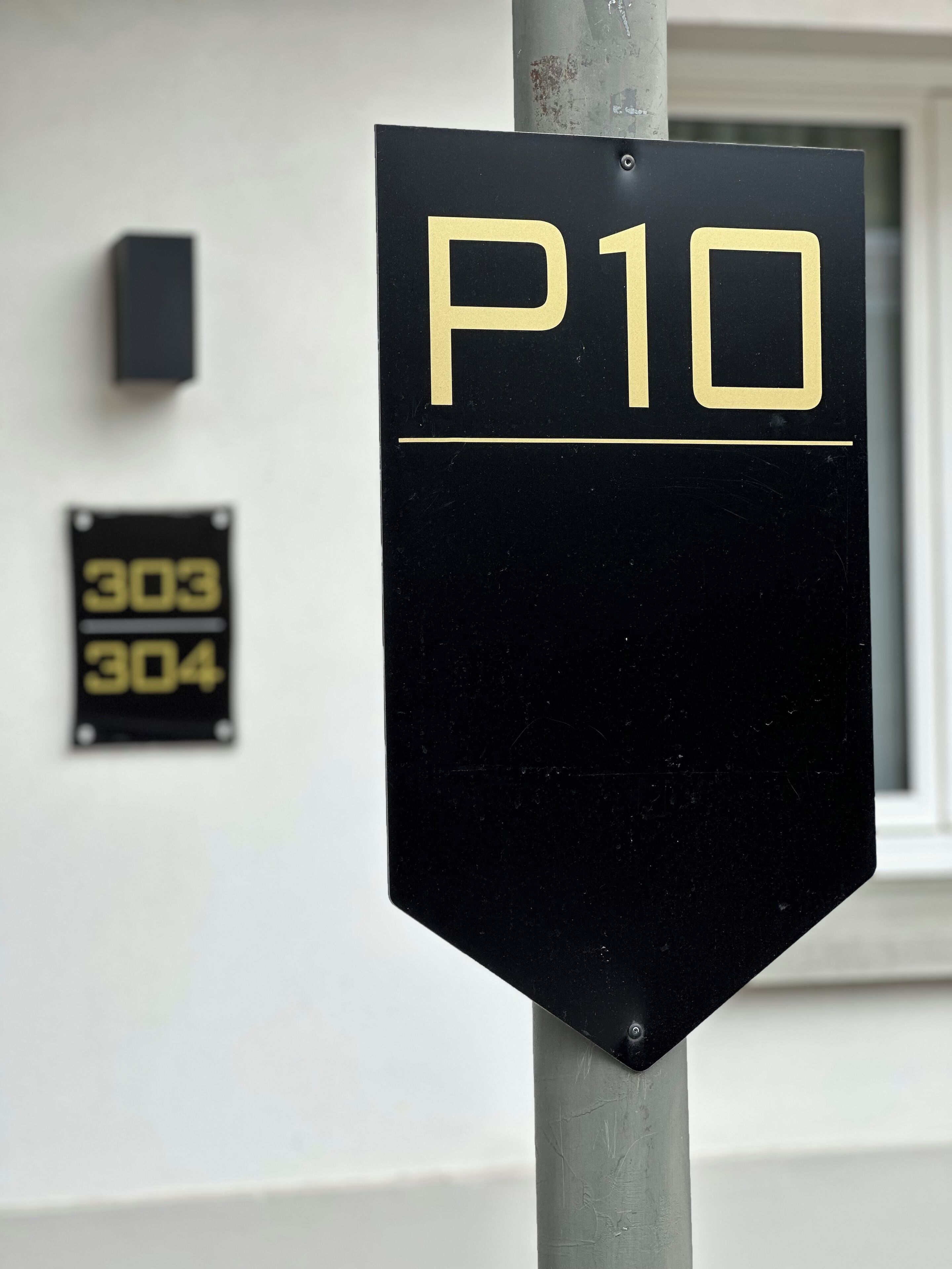 A black sign with 'P10' in gold letters, mounted on a metal pole.