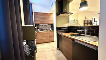 Een moderne keuken met houten kastjes, een zwart betegelde achterwand en een roestvrijstalen spoelbak.