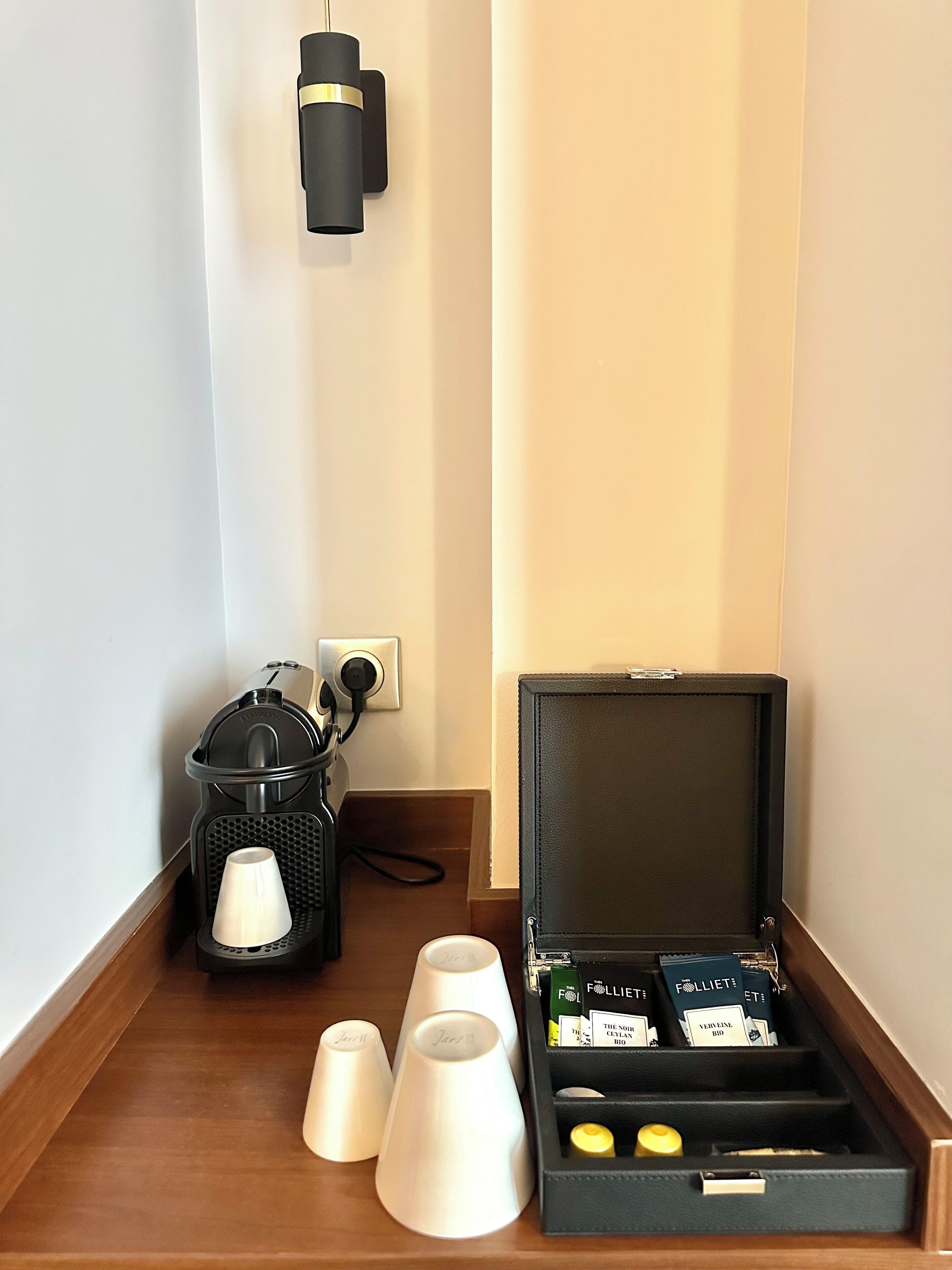 Eine Kaffeemaschine, eine Steckdose und eine Aufbewahrungsbox mit Fächern, die eine gelbe Flasche und einen weißen Behälter enthalten.