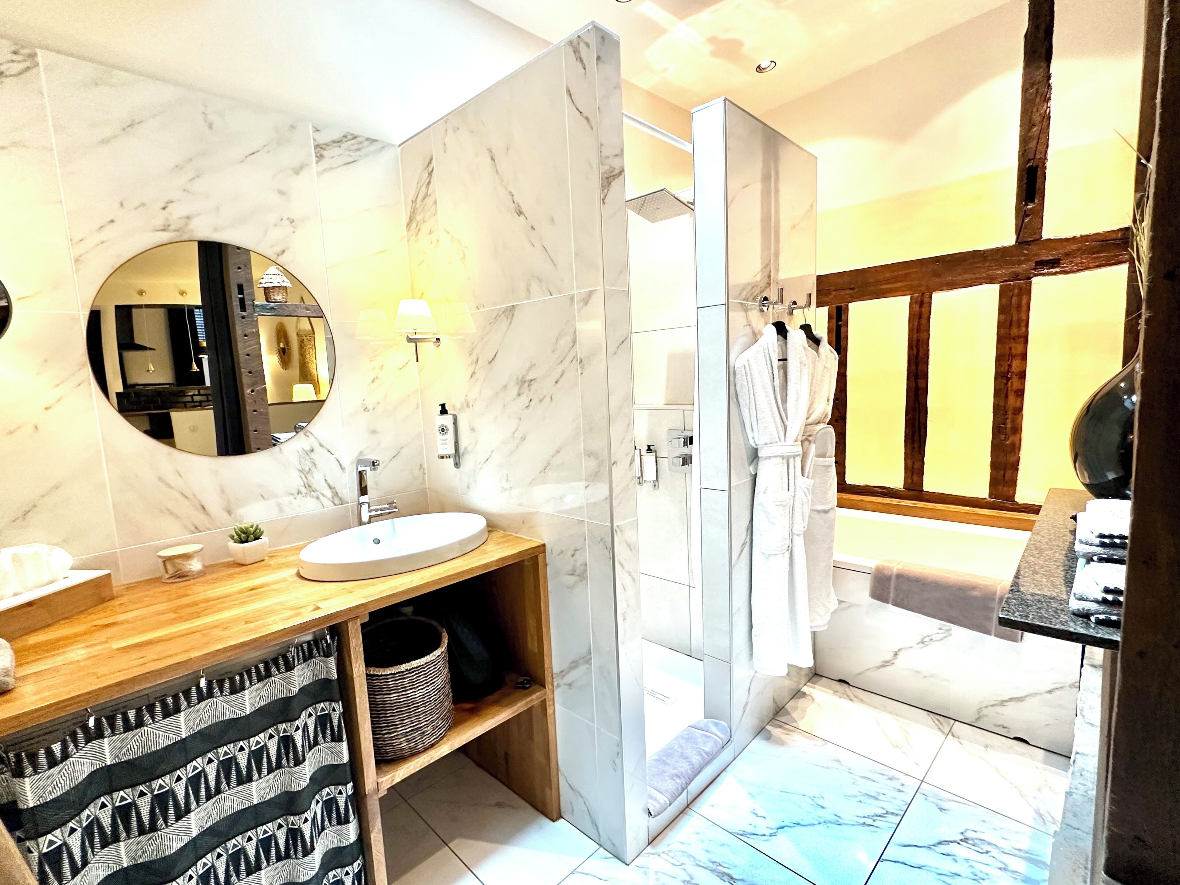 A bathroom with a marble vanity, a sink, a mirror, a shower, and a wooden door.