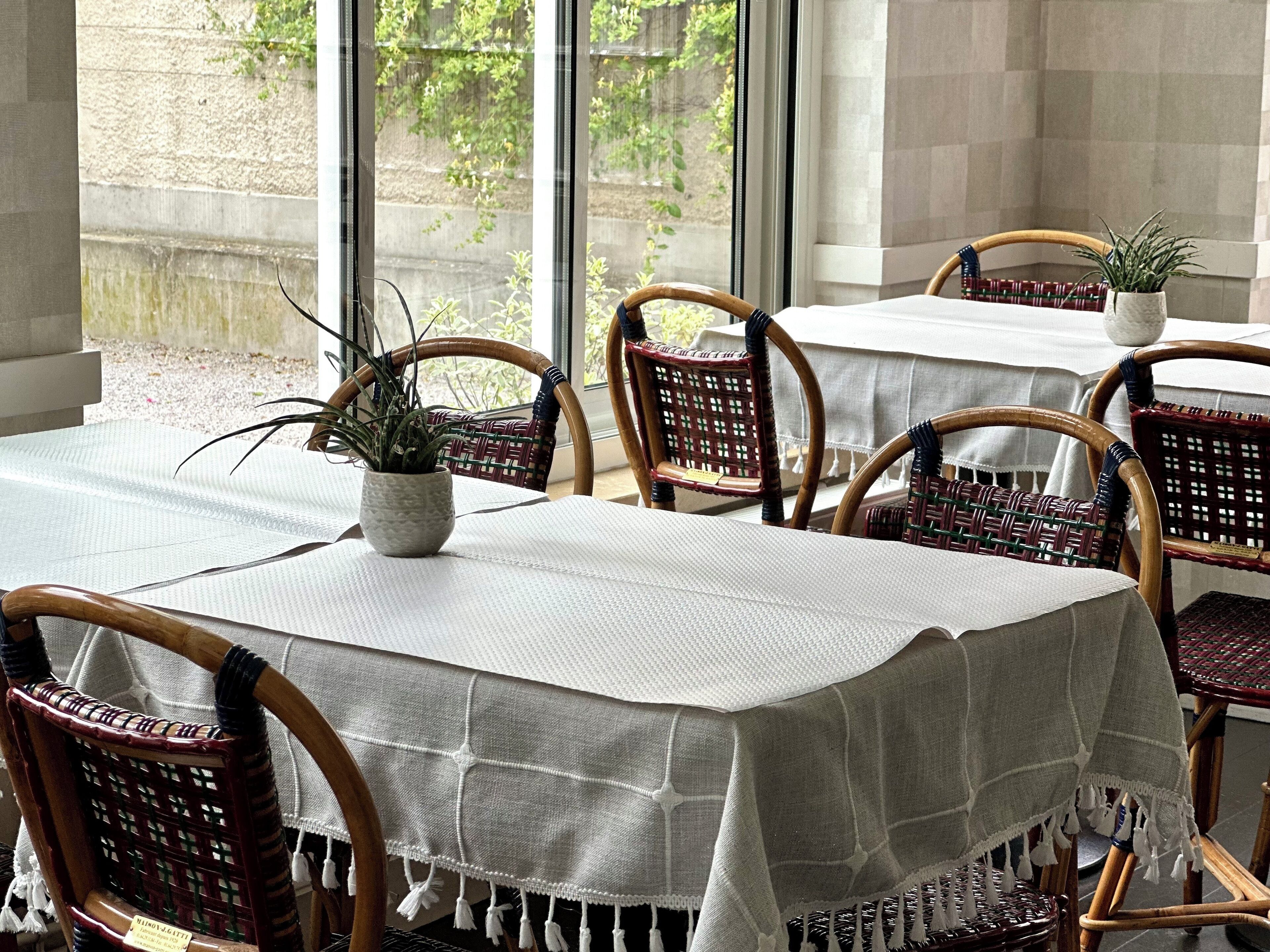 A dining area with wicker chairs and a table covered with a white tablecloth.
