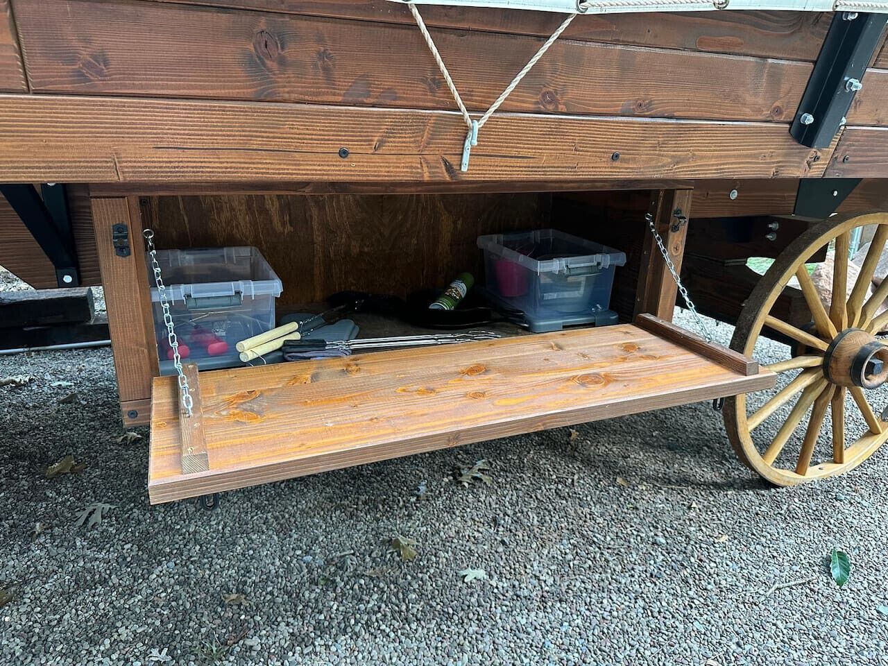 A wooden cart with storage compartments and a flat surface.