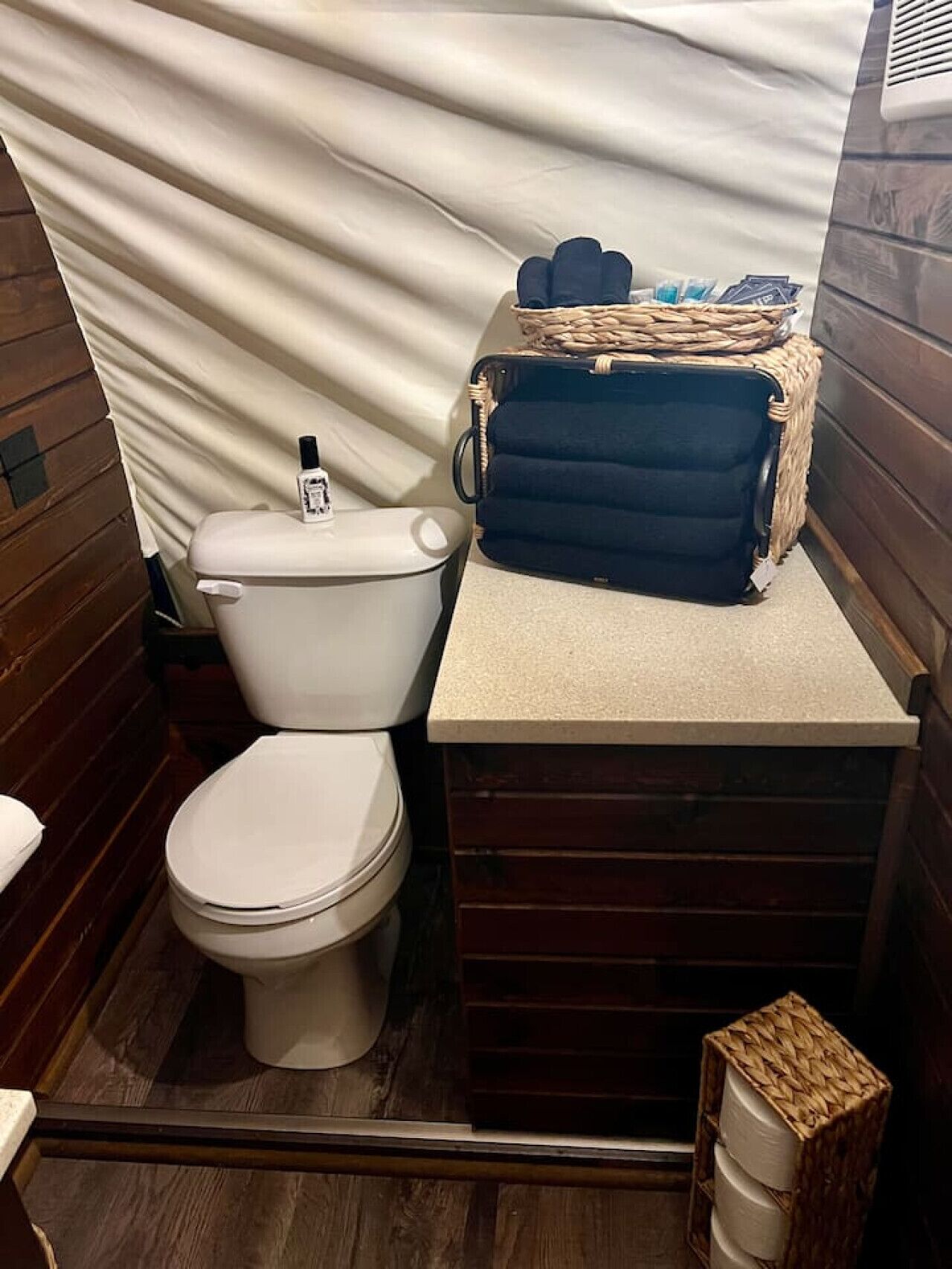 Et lille badeværelse med toilet, vask og en kurv med toiletartikler.