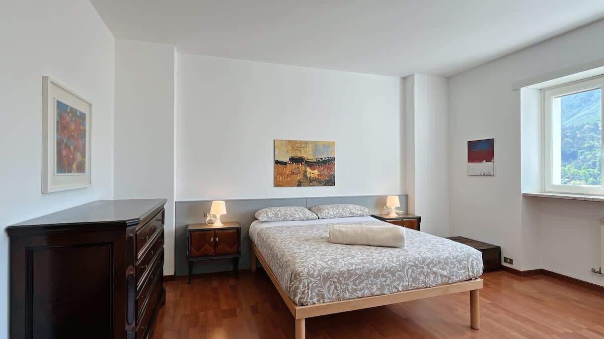 Un dormitorio con una cama, dos mesitas de noche, un aparador y obras de arte en las paredes.
