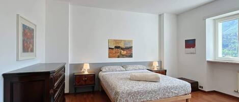 Un dormitorio con una cama, dos mesitas de noche, un aparador y obras de arte en las paredes.