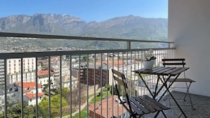Ein Balkon mit Blick auf eine Stadtlandschaft und Berge.