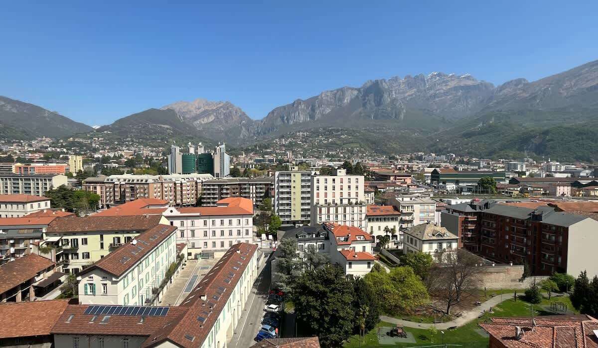 A cityscape with a mix of modern and traditional buildings, a prominent church, and mountains in the background.