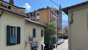 A narrow street with buildings on both sides, a bar named "bar baff" on the left, and parked cars. - Welcome House - Affitti Brevi italia (Lecco)