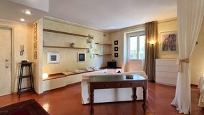 A room with a bed, a table, a sofa, and a window with curtains. - Welcome House - Affitti Brevi italia (Lecco)