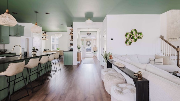 Une cuisine moderne avec des tabourets de bar, un coin repas avec un canapé et un couloir menant au salon.