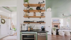 A kitchen with wooden shelves, a refrigerator, and a dining area with a sofa.