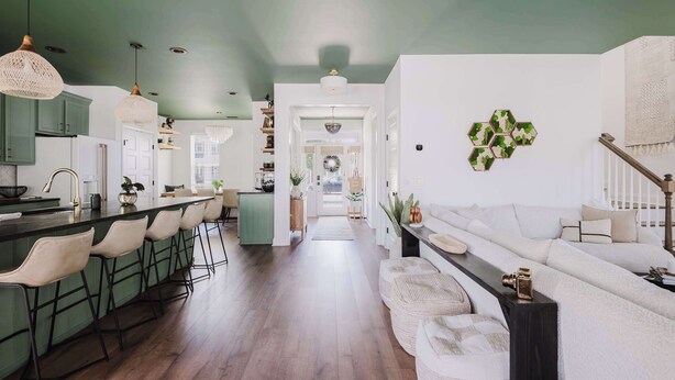 A modern kitchen with a bar area, a dining space with a sofa, and a hallway leading to a living area.
