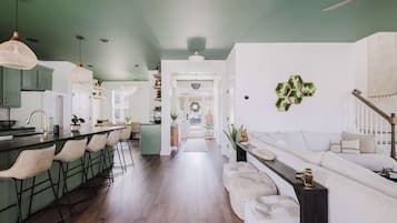 A modern kitchen with a bar area, a dining space with a sofa, and a hallway leading to a living area.