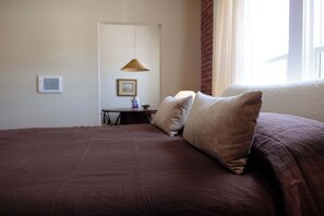 A hotel room with a large bed, a small table with a lamp, and a window with curtains. - The Hollywood Sign Lookout (Los Angeles)