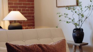 Ein Zimmer mit einer Couch, einer Lampe, einem gerahmten Bild und einer Topfpflanze.