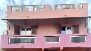 A two-story building with a pink facade, a wooden door, and a garage. - CHEZ TITI: SAFETY & COMFORT IN ST LOUIS (Saint-Louis)