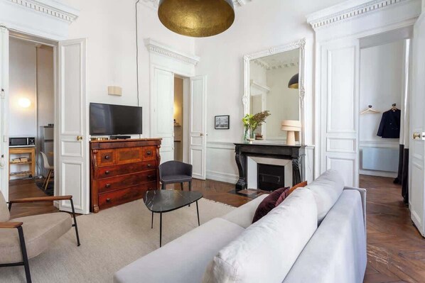 A living room with a sofa, a TV, a wooden dresser, and a fireplace.