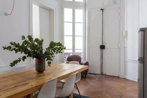 A dining area with a wooden table, white chairs, and a potted plant.