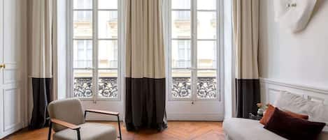 A room with a sofa, a chair, a coffee table, and a window with curtains.