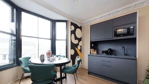 Une cuisine moderne équipée d’un four à micro-ondes, d’une machine à café et de placards. Un coin repas avec une table et des chaises est également à disposition.