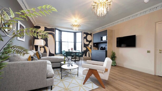 Un salon moderne comprenant un canapé, un fauteuil, une table basse et un lustre.