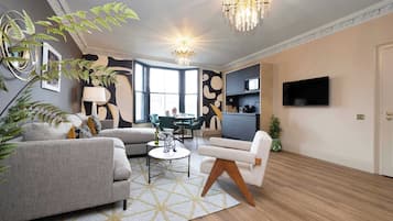 A modern living room with a sofa, armchair, coffee table, and a chandelier.