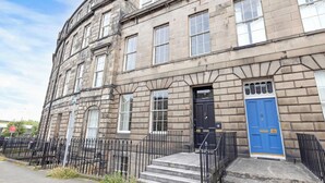 A historic building with a blue door, stone facade, and black iron railings.