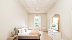 A bedroom with a bed, bedside tables, a dresser, a mirror, and a window.