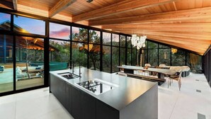 Una cocina moderna con una isla grande, armarios negros y vistas al exterior.