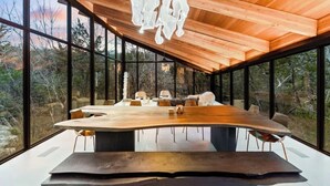Un comedor moderno con una amplia mesa de madera y sillas, grandes ventanales que ofrecen vistas del paisaje circundante.