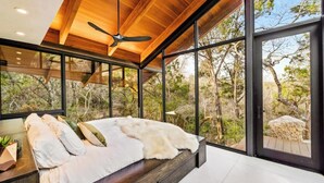 Un dormitorio moderno con una cama grande, techo de madera y vistas al exterior.