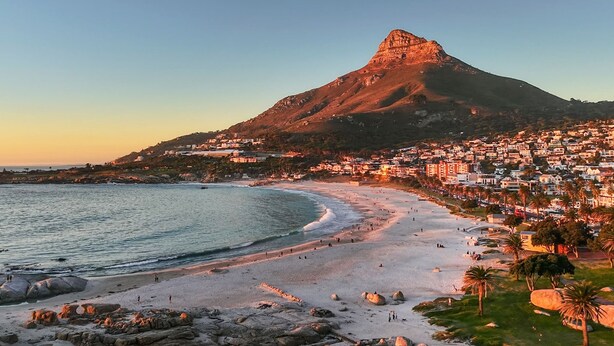 A coastal town with a prominent mountain, a sandy beach, and a densely built residential area.