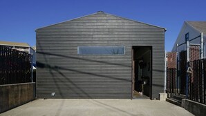 A small, dark wooden shed with a single door and a small window.
