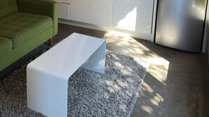 A modern kitchen with white cabinets, a stainless steel refrigerator, and a green sofa.