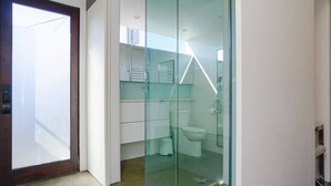 A modern bathroom with a glass shower enclosure, a toilet, and a sink.