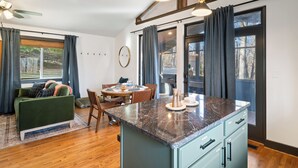 Une cuisine moderne dotée d’un plan de travail en marbre, de meubles en bois et d’un coin repas avec une table et des chaises.