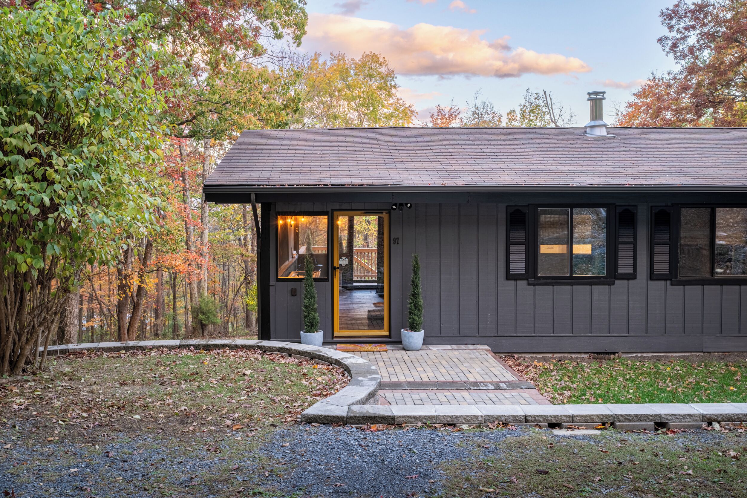 A modern house with a dark exterior, a front door, and a small porch area.